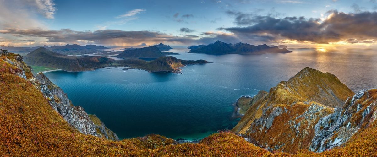A panoramic shot of the hill Veggen near the sea under a blue sky in Norway